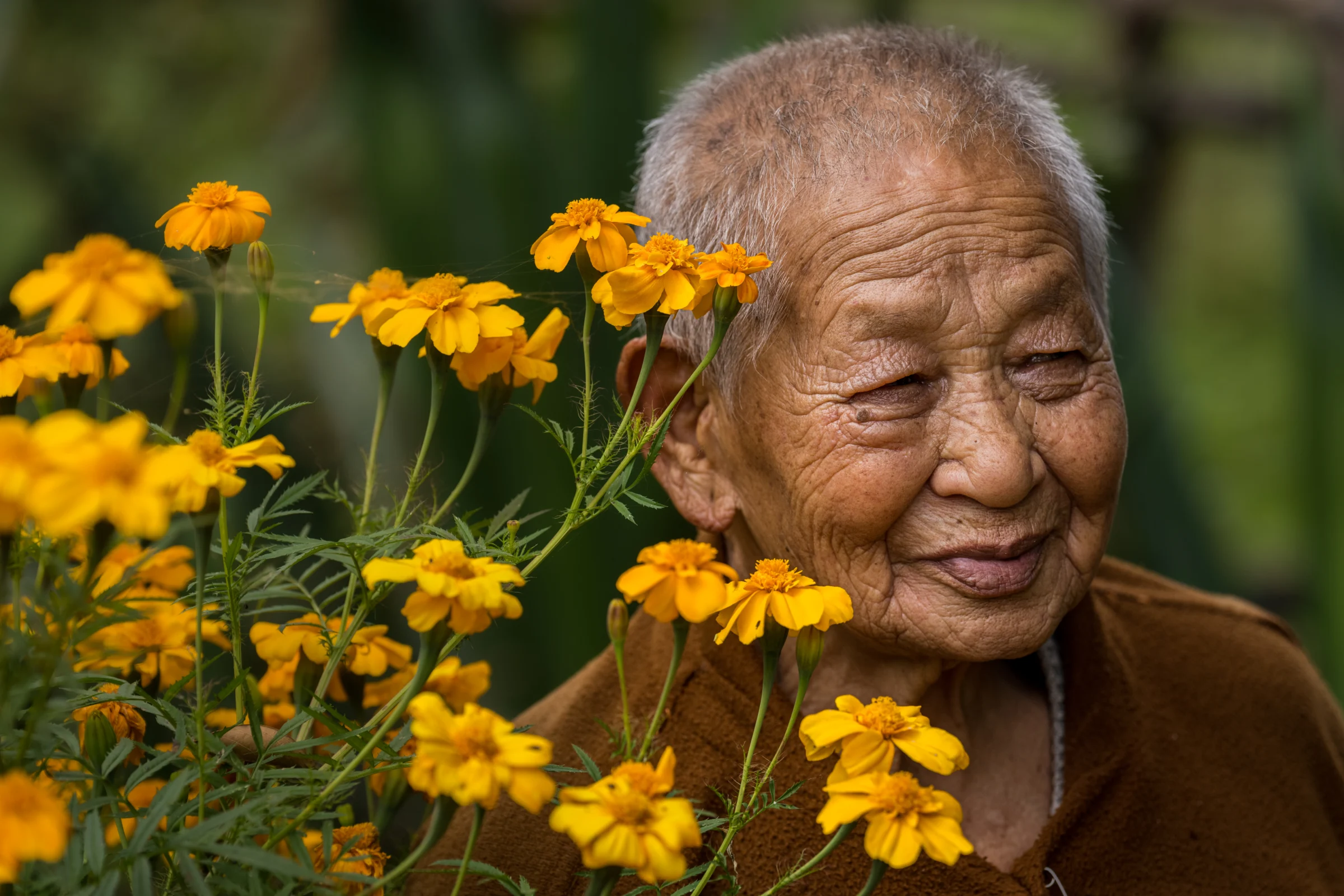 A Bhutanese elder smiling among marigold flowers