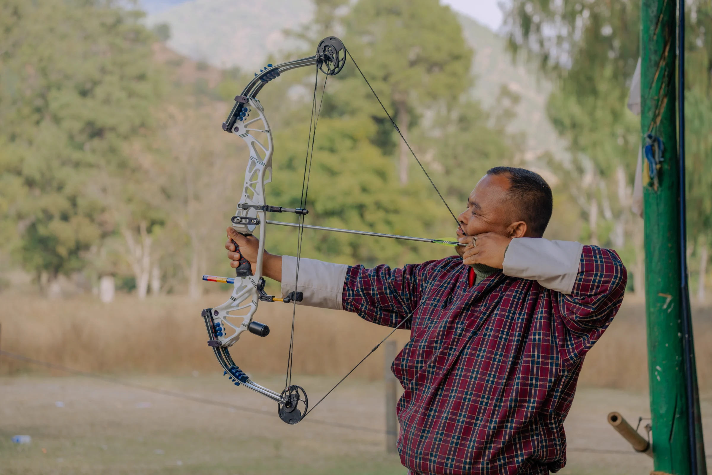 A Bhutanese archer drawing a bow at a traditional archery ground